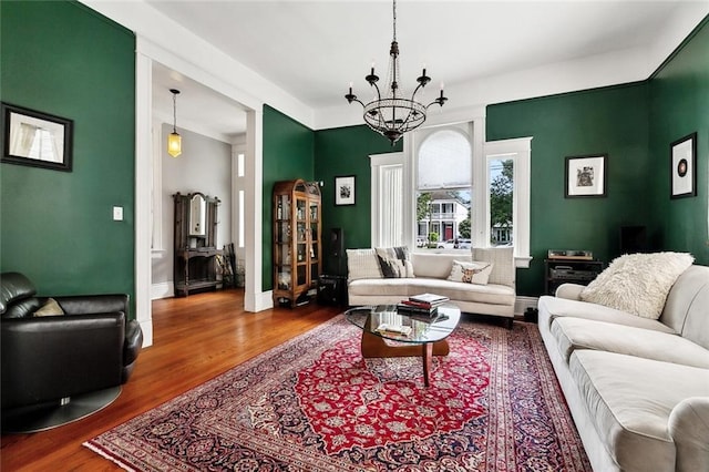 living area featuring a chandelier, wood finished floors, and baseboards