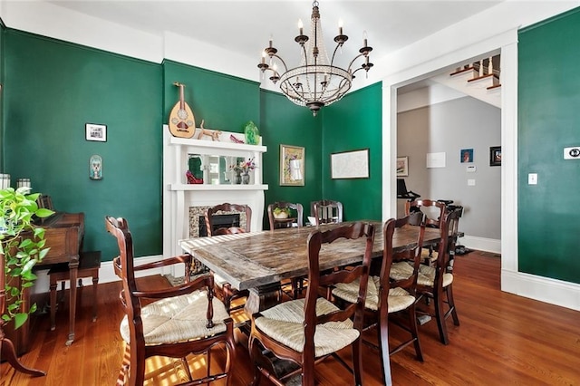 dining space with a chandelier, wood finished floors, baseboards, and a fireplace