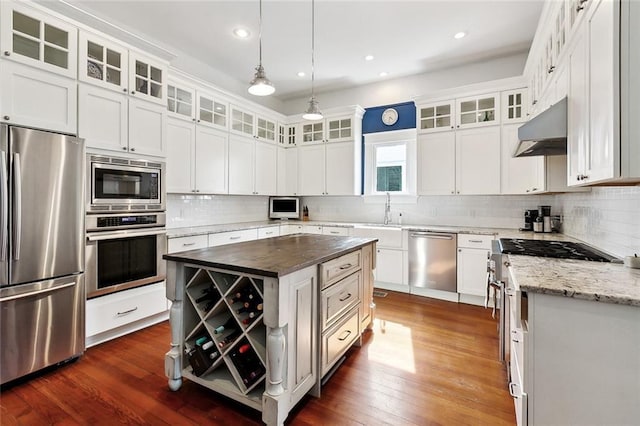 kitchen with appliances with stainless steel finishes, under cabinet range hood, decorative backsplash, white cabinetry, and recessed lighting