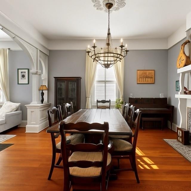5925 Annunciation St, New Orleans, LA 70115 - dining space with a chandelier, wood finished floors, arched walkways, and decorative columns