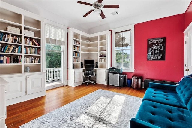 living room featuring ceiling fan, a desk, plenty of natural light, and wood finished floors