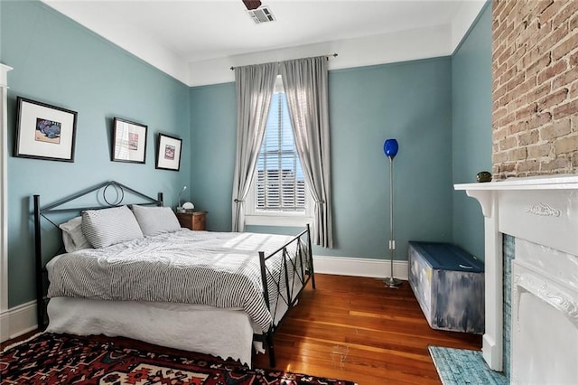 bedroom featuring hardwood / wood-style floors, baseboards, and a fireplace