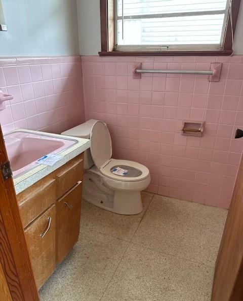 2258 General Collins Ave, New Orleans, LA 70114 - half bathroom featuring tile walls, toilet, a wainscoted wall, vanity, and healthy amount of natural light