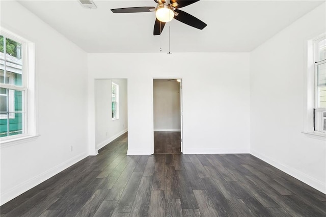 empty room featuring healthy amount of natural light, a ceiling fan, and dark wood-style flooring