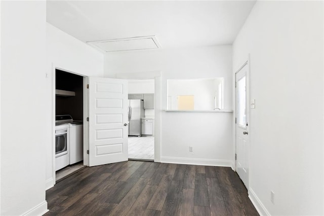 unfurnished bedroom with freestanding refrigerator, washing machine and clothes dryer, dark wood-style floors, and baseboards