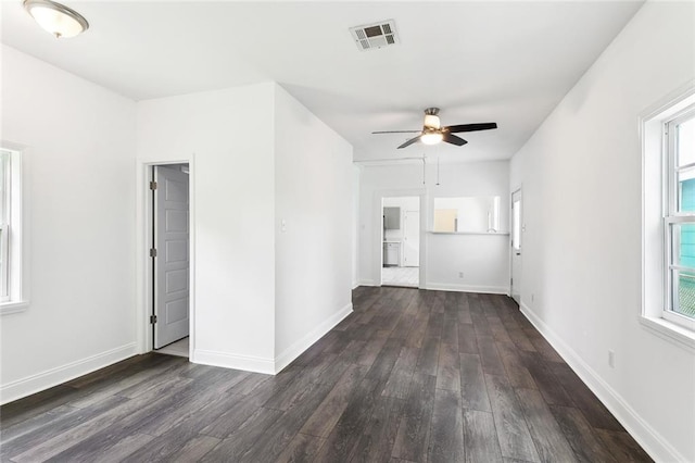 unfurnished living room with dark wood-style flooring, a ceiling fan, plenty of natural light, and baseboards