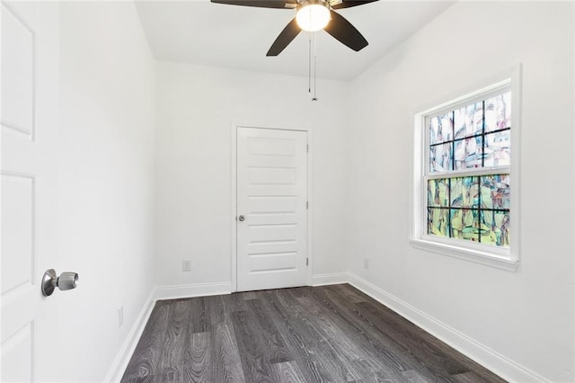 unfurnished room featuring dark wood-style flooring, a ceiling fan, and baseboards