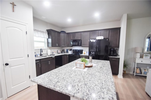kitchen with black appliances, dark brown cabinets, a sink, light wood-style flooring, and recessed lighting