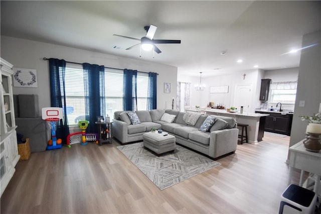 living area featuring a chandelier, ceiling fan, light wood-style floors, and recessed lighting