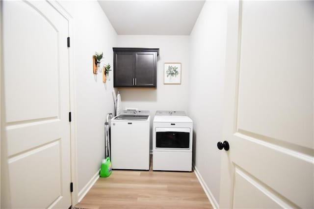 laundry room with cabinet space, washing machine and dryer, light wood finished floors, and baseboards