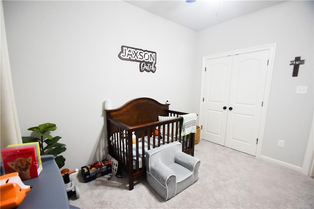 bedroom featuring a crib, carpet floors, a closet, and baseboards
