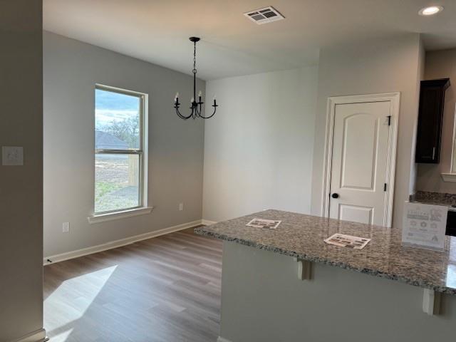 unfurnished dining area featuring a chandelier, light wood-type flooring, baseboards, and recessed lighting