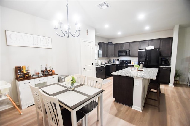 kitchen with black appliances, light wood-style floors, a chandelier, a center island, and recessed lighting