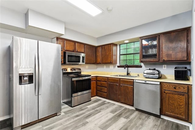 19635 Sunshine Ave, Covington, LA 70433 - kitchen featuring stainless steel appliances, light countertops, light wood-style floors, and glass insert cabinets