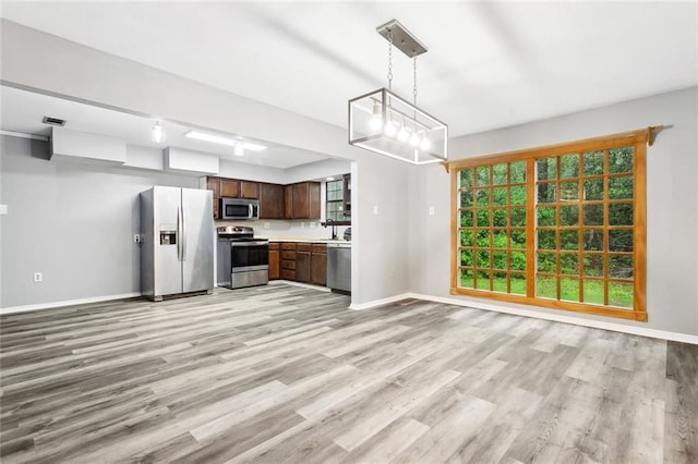19635 Sunshine Ave, Covington, LA 70433 - kitchen featuring stainless steel appliances, light wood finished floors, light countertops, dark brown cabinetry, and decorative light fixtures