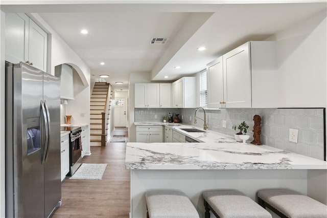 240810 Saint Anthony St, New Orleans, LA 70119 - kitchen featuring stainless steel appliances, a sink, a peninsula, wood finished floors, and recessed lighting