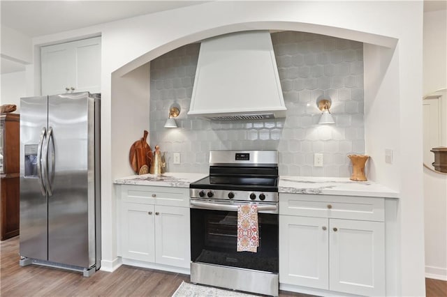 240810 Saint Anthony St, New Orleans, LA 70119 - kitchen featuring appliances with stainless steel finishes, light wood-style flooring, backsplash, and white cabinets