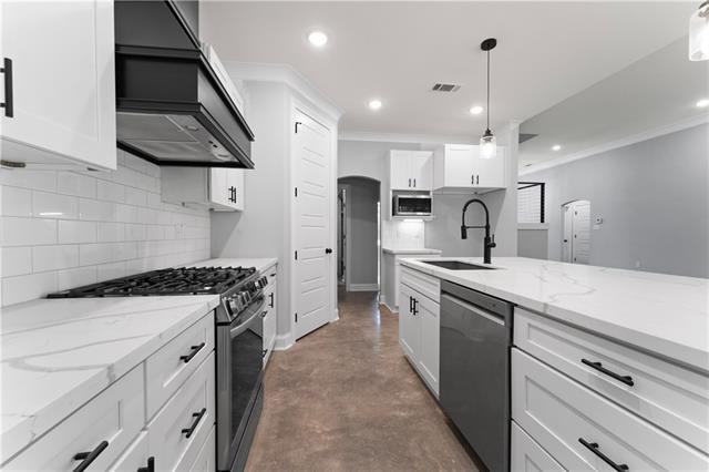43448 Springwood Way, Hammond, LA 70401 - kitchen featuring stainless steel appliances, custom exhaust hood, tasteful backsplash, finished concrete flooring, and white cabinetry