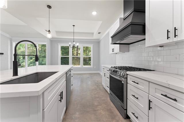 43448 Springwood Way, Hammond, LA 70401 - kitchen featuring appliances with stainless steel finishes, custom range hood, a raised ceiling, backsplash, and concrete flooring