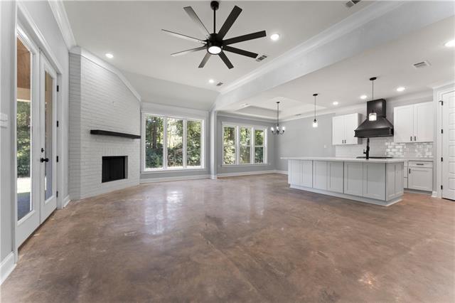 43448 Springwood Way, Hammond, LA 70401 - unfurnished living room featuring finished concrete floors, ornamental molding, a fireplace, recessed lighting, and a chandelier