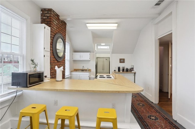 2224 Dumaine St, New Orleans, LA 70119 - kitchen with a peninsula, light countertops, white cabinetry, and a breakfast bar