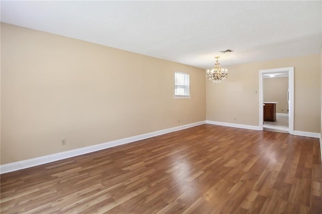 5120 Belle Dr, Metairie, LA 70006 - empty room with a chandelier, wood finished floors, baseboards, and a textured ceiling