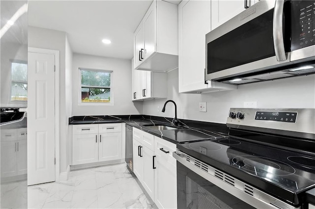 kitchen featuring appliances with stainless steel finishes, a sink, light marble finish flooring, white cabinetry, and recessed lighting