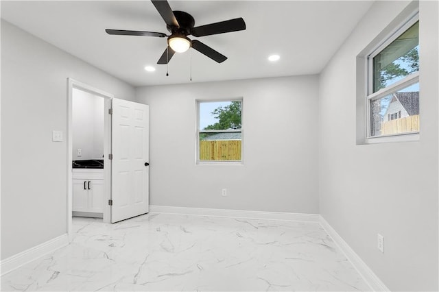 spare room featuring plenty of natural light, light marble finish floors, baseboards, and recessed lighting
