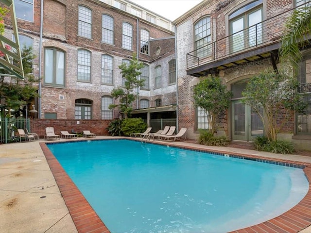 community pool with a patio, french doors, and fence