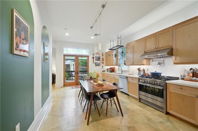 3217 Dauphine St, New Orleans, LA 70117 - kitchen with stainless steel appliances, under cabinet range hood, decorative backsplash, a sink, and light countertops