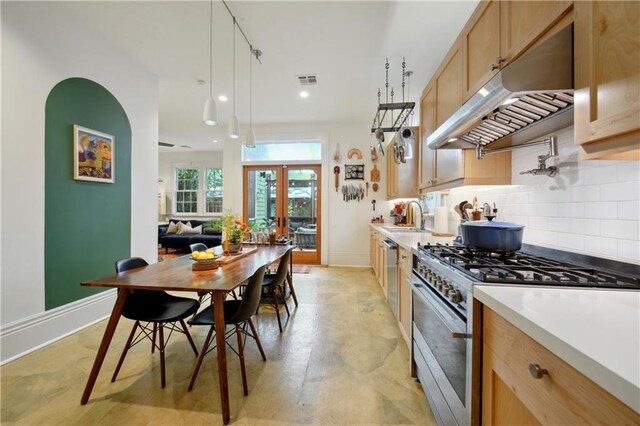 3217 Dauphine St, New Orleans, LA 70117 - kitchen with stainless steel appliances, under cabinet range hood, tasteful backsplash, baseboards, and light brown cabinets