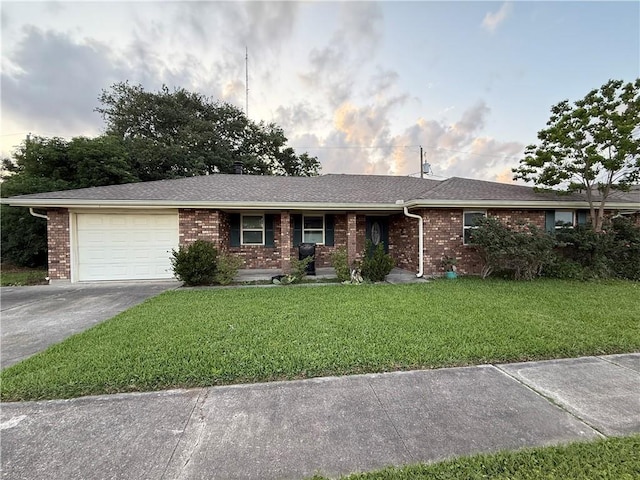 single story home with an attached garage, a front lawn, concrete driveway, and brick siding