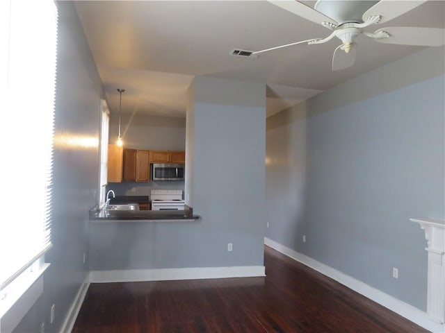 kitchen with stainless steel microwave, white range with electric cooktop, dark wood-style floors, baseboards, and ceiling fan