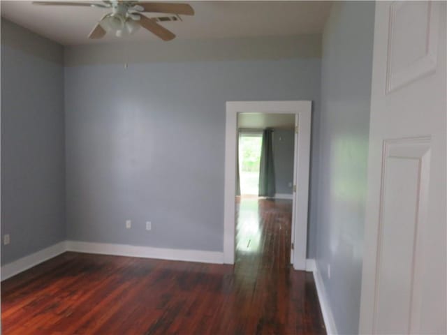 empty room with ceiling fan, dark wood-style flooring, and baseboards