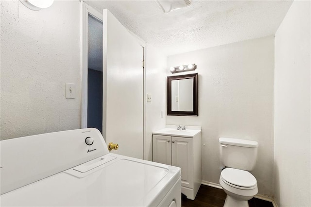 27 Pinewood Ct, New Orleans, LA 70114 - bathroom featuring washer / clothes dryer, a textured ceiling, wood finished floors, vanity, and toilet