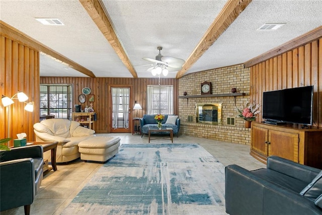 41376 Dunson Rd, Ponchatoula, LA 70454 - tiled living room featuring a textured ceiling, beamed ceiling, a ceiling fan, wood walls, and a brick fireplace