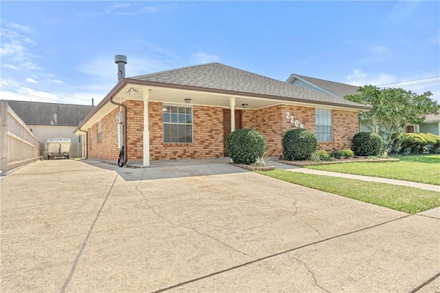 view of front of property featuring driveway, brick siding, a front yard, and roof with shingles