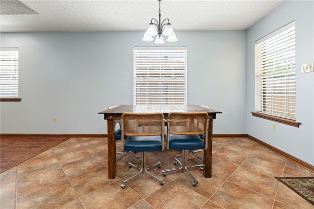 dining space featuring a chandelier, a textured ceiling, baseboards, and tile patterned floors