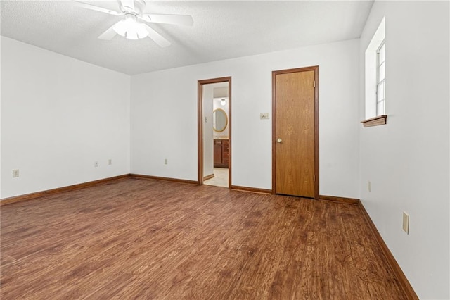 spare room featuring wood finished floors, a ceiling fan, and baseboards