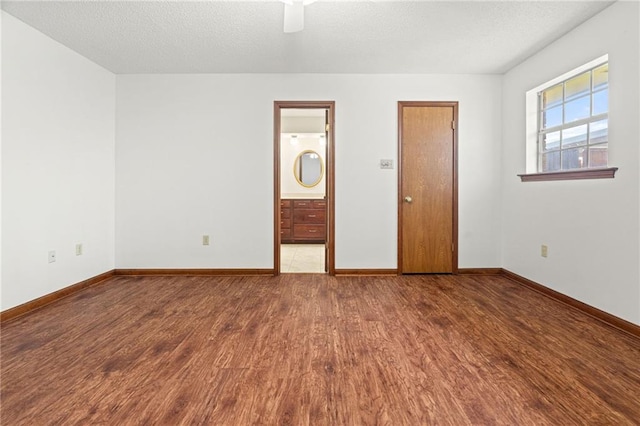 unfurnished room with wood finished floors, baseboards, washer / dryer, ceiling fan, and a textured ceiling