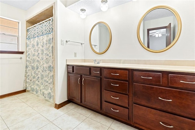 bathroom with tile patterned flooring, baseboards, vanity, and curtained shower
