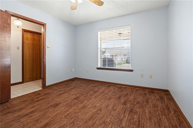 unfurnished room with wood finished floors, a textured ceiling, a ceiling fan, and baseboards