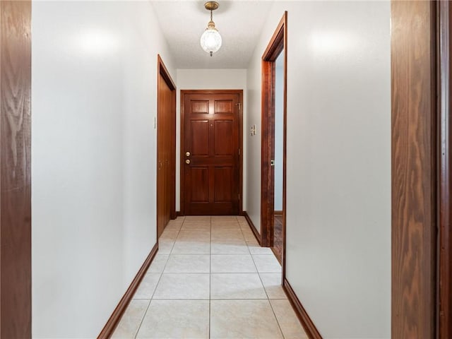hall featuring light tile patterned floors and baseboards