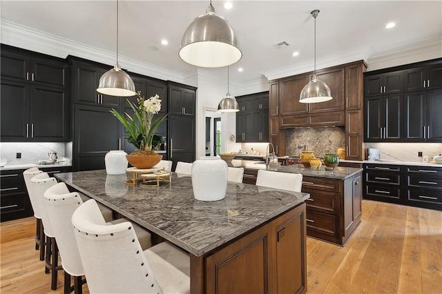 181 Windermere Way, Madisonville, LA 70447 - kitchen featuring a center island with sink, tasteful backsplash, dark stone countertops, recessed lighting, and a kitchen bar