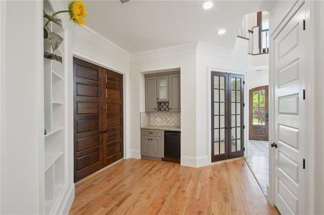 bar area featuring french doors, dishwasher, tasteful backsplash, ornamental molding, and light wood-type flooring