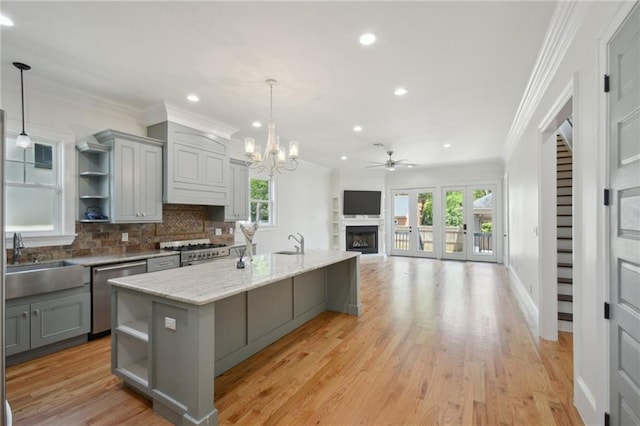 kitchen with gray cabinets, open shelves, appliances with stainless steel finishes, a sink, and crown molding