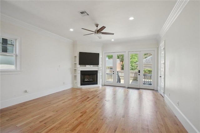 unfurnished living room with crown molding, ceiling fan, light wood-type flooring, a fireplace with raised hearth, and baseboards