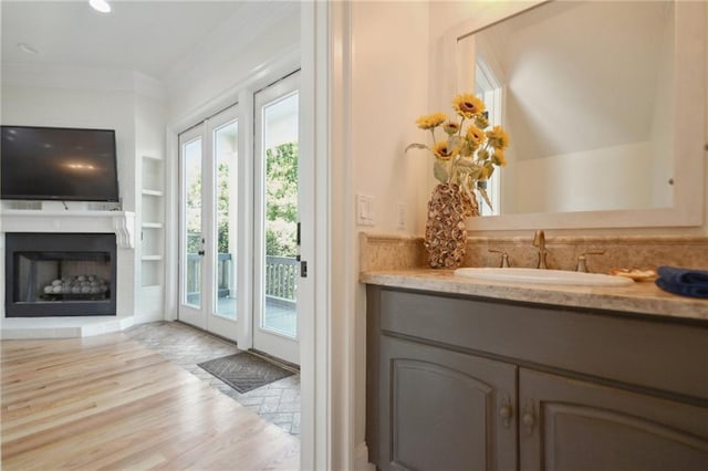 doorway to outside with a sink, wood finished floors, built in features, crown molding, and a fireplace