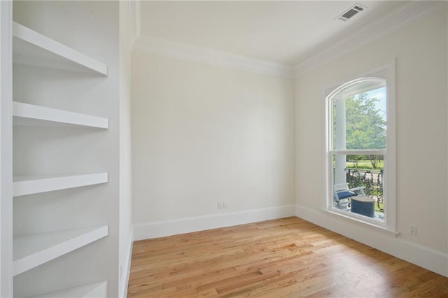 unfurnished room with ornamental molding, light wood-type flooring, and baseboards