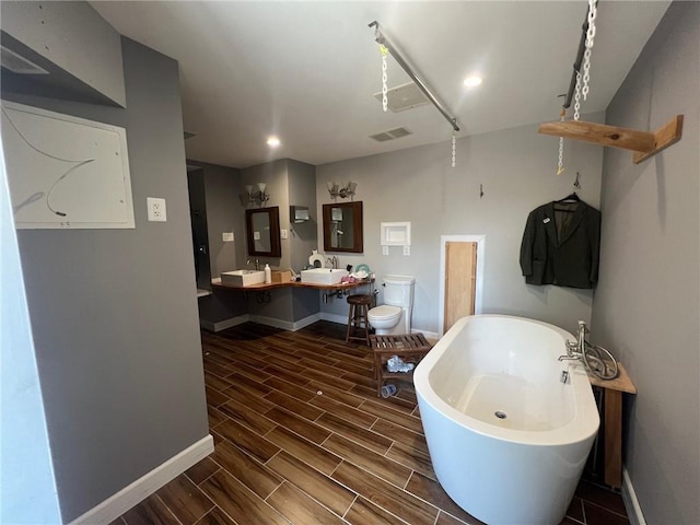 200 Macque St, Harahan, LA 70123 - bathroom with a freestanding tub, baseboards, wood tiled floors, double vanity, and recessed lighting